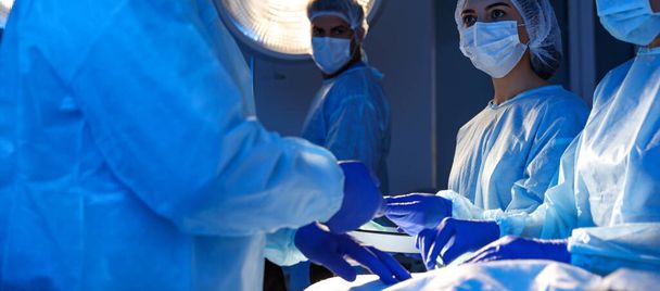 Profesyonel doktorlardan oluşan bir ekip ameliyathanede ameliyat yapıyor. Pankart tasarımı - Fotoğraf, Görsel