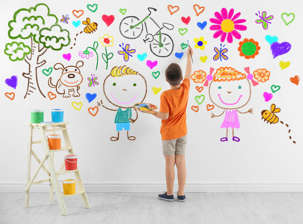 Cute child boy drawing of colorful dye many different picture on white wall - Фото, зображення