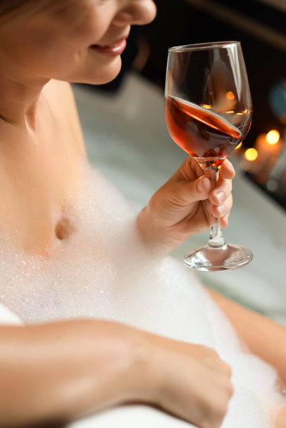 Femme buvant du vin tout en prenant un bain moussant, gros plan. Ambiance romantique - Photo, image