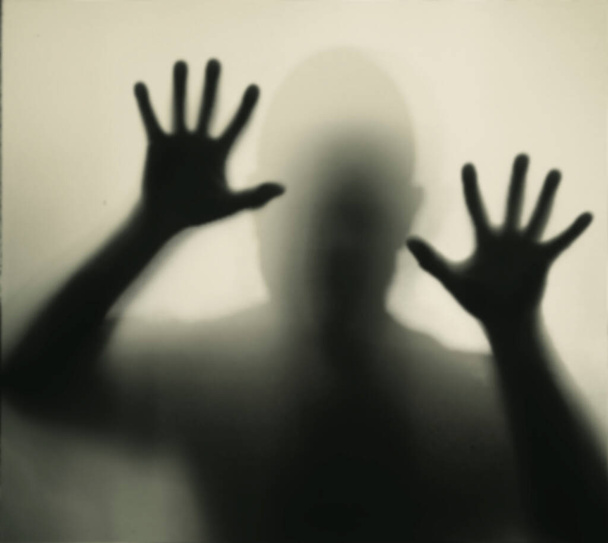 Horror, halloween background - Shadowy figure behind glass of a man - Fotó, kép