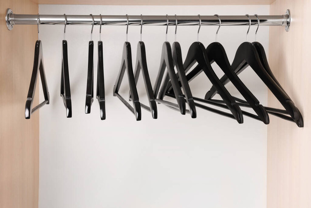 Set of black clothes hangers on wardrobe rail - Foto, afbeelding