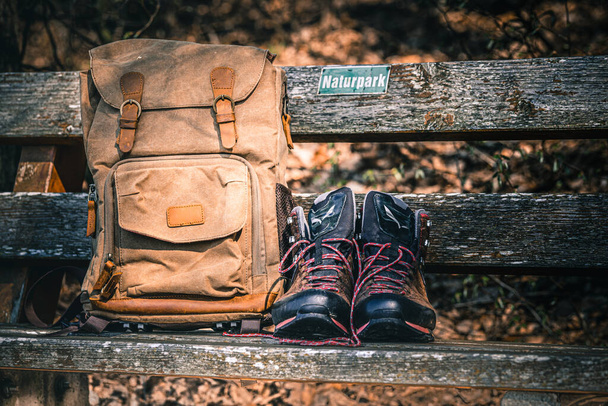 A photo of a retro backpack and hiking boots on a wooden bench, hiking gear - Photo, image