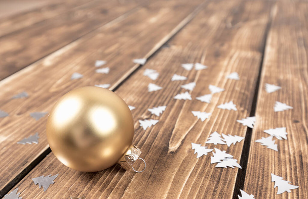 A closeup shot of a golden color Christmas decoration on a wooden table - Foto, Imagem