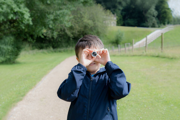 Kind schaut durch Mini-Mikroskop mit staunendem Gesicht, Aufgeregtes Kind auf einem Klassenausflug im grünen Wald, Entdecker mit Wildtieren im Sommerlager, Reise- und Bildungskonzept - Foto, Bild