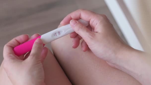 Felismerhetetlen nő terhességi tesztet csinál a fürdőszobában. Pozitív terhességi tesztet tartó lány két vonallal. Közelkép a terhességi teszt készlet a kezében. - Felvétel, videó