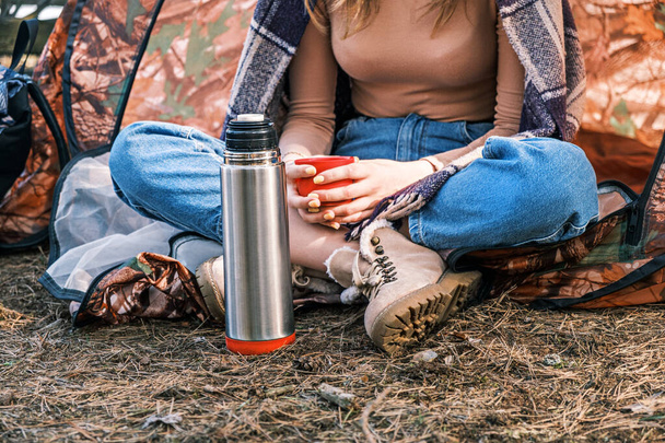 秋の森の中のテントに座っている少女が手にお茶を持っている。精神衛生だ。自分一人で時間、熟考。セルフケア - 写真・画像