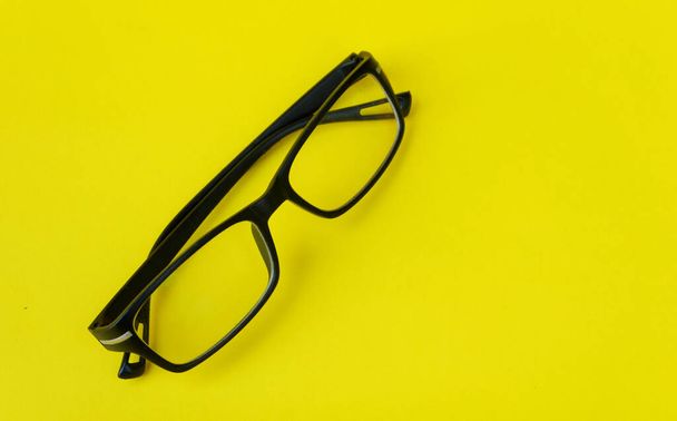 An angle shot of optical glasses on a yellow background with copy space. - Zdjęcie, obraz