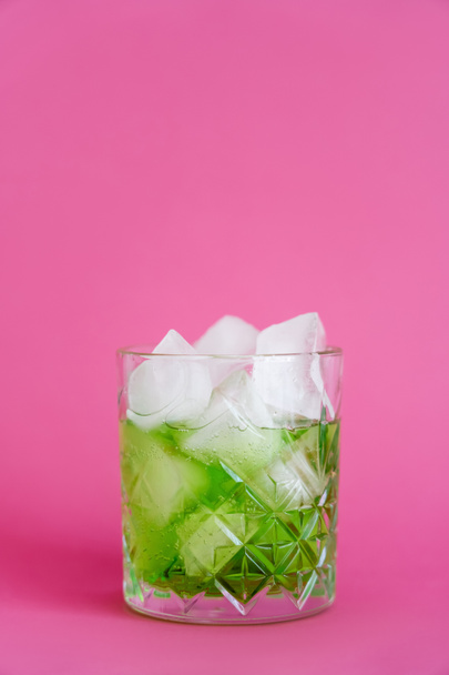 frozen ice cubes in glass with green mojito drink on pink  - Φωτογραφία, εικόνα