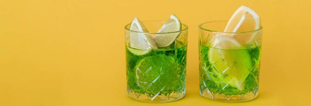 sliced citrus fruits in glasses with sparkling mojito drink on yellow, banner - Valokuva, kuva