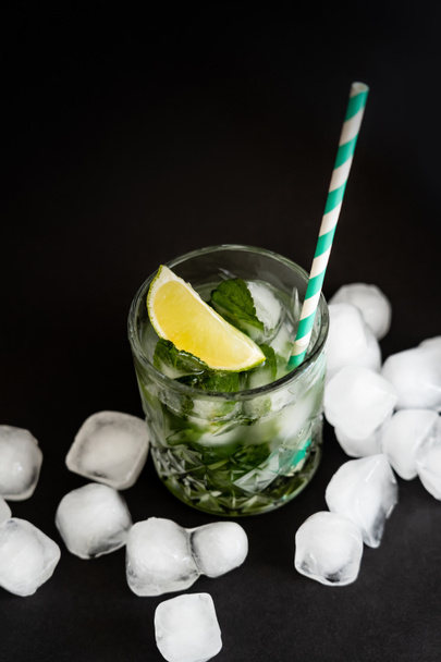 high angle view of cool faceted glass with mojito near ice cubes on black  - Photo, Image