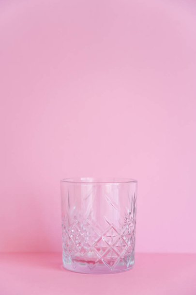empty and transparent faceted glass on pink background  - Foto, imagen