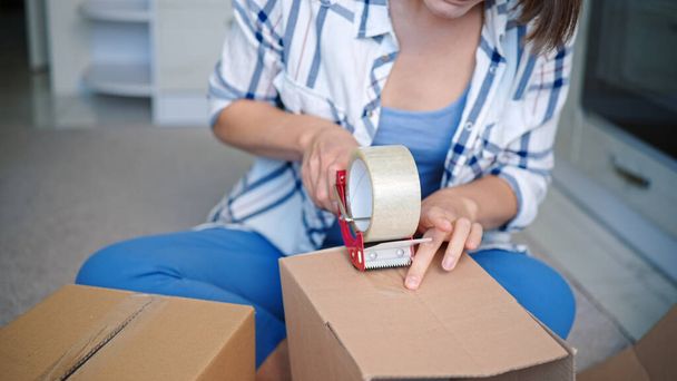 A closeup shot of a Caucasian woman packaging the boxes - Foto, afbeelding