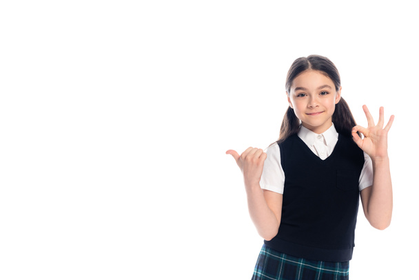 Smiling schoolgirl gesturing and looking at camera isolated on white  - Fotografie, Obrázek