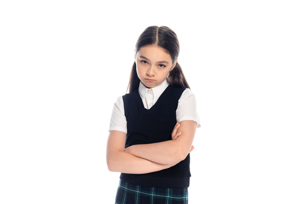 Upset schoolgirl crossing arms and looking at camera isolated on white  - Foto, Bild