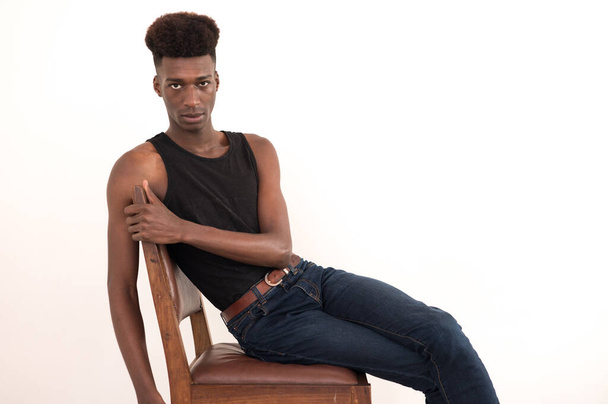 Young man seen sitting on chair while looking at camera - Photo, Image
