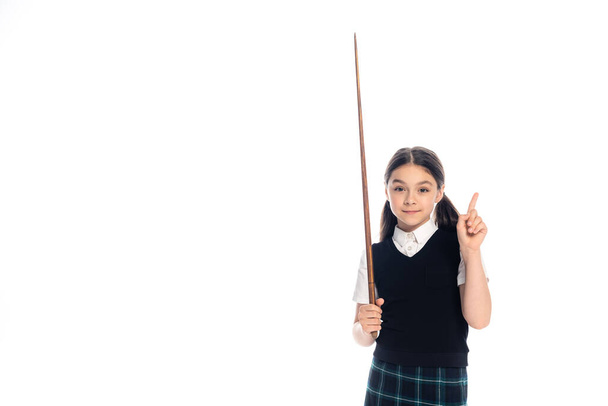 Schoolgirl holding pointer and pointing with finger isolated on white  - Foto, Imagen