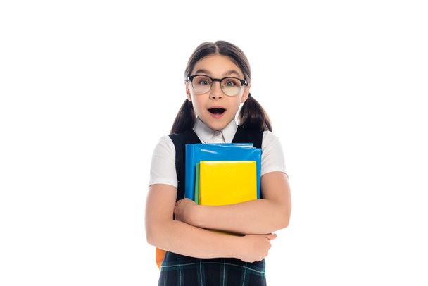 Shocked schoolkid with backpack holding books and looking at camera isolated on white  - Φωτογραφία, εικόνα