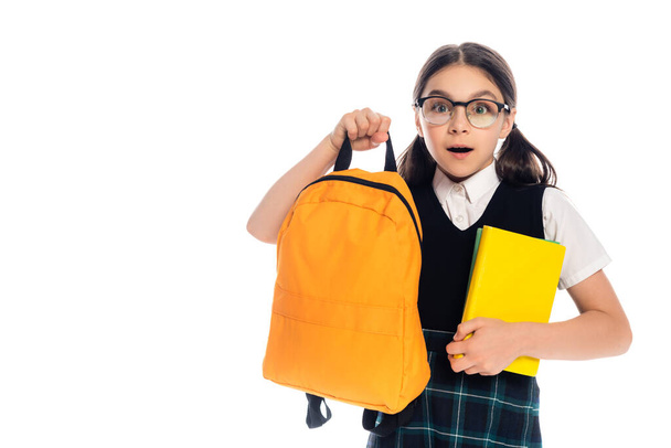 Shocked schoolkid holding books and backpack isolated on white  - Photo, Image
