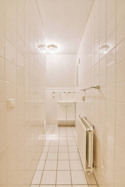 Wall hung toilet and small sink in corner in lavatory room with beige tile - Foto, Bild