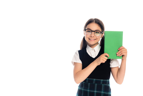 Positive schoolkid in eyeglasses holding book isolated on white  - Photo, Image