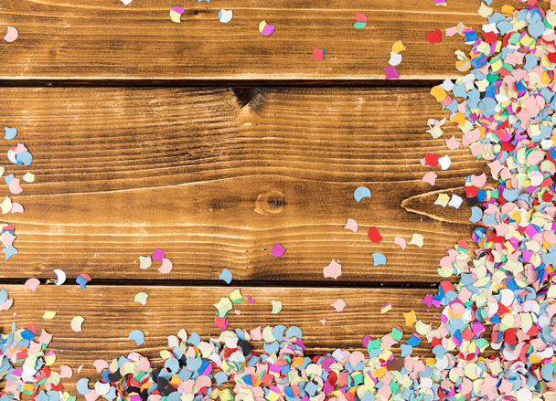 A top view of multicolored confetti and streamers on a wooden table - Foto, immagini