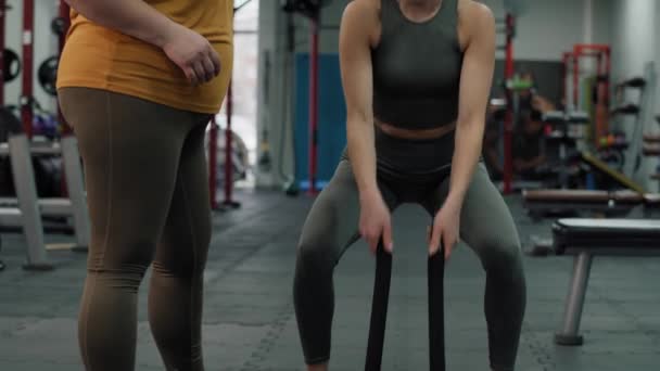 Blanke vrouwelijke trainer die laat zien hoe je een oefening maakt met touw in de sportschool. Opgenomen met RED helium camera in 4K.   - Video