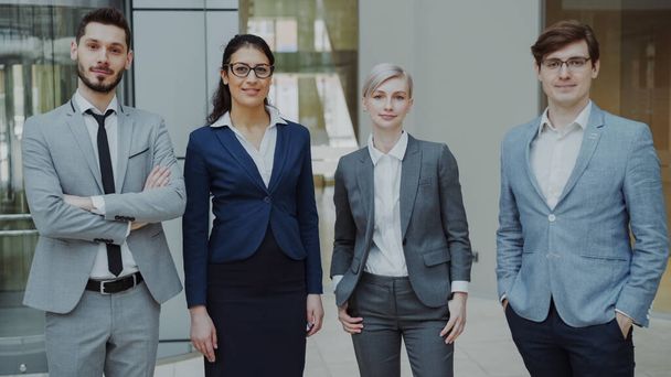 Portrait of group of business people smiling in modern office indoors. Team of businessmen and businesswomen standing together - Foto, afbeelding