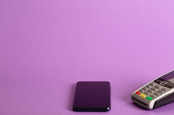 Uma foto de close-up da máquina de cartão de crédito do terminal POS e um telefone em um fundo rosa - Foto, Imagem