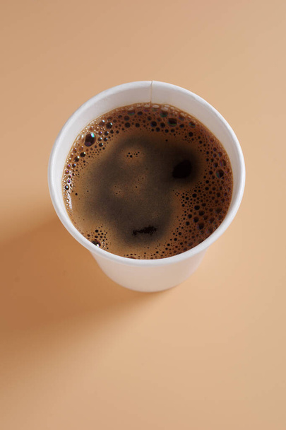 Cartão descartável xícara de café no fundo bege, vista superior. Louça descartável de papel ecológico - Foto, Imagem