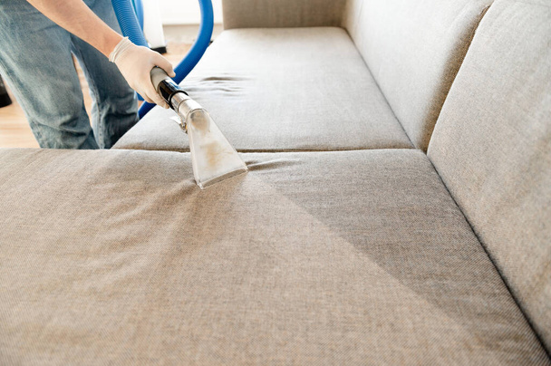 Сотрудник химчистки убирает грязь с мебели в квартире
 - Фото, изображение