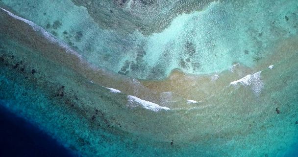 An aerial drone view of a beautiful tropical island with clear water and calm foamy waves - Foto, Bild
