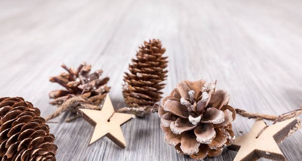 A closeup shot of a christmas ribbon with pine cones on a wooden table - Zdjęcie, obraz