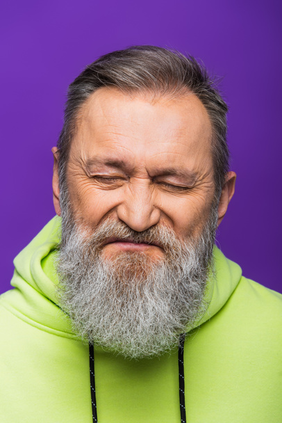 portrait of senior man with grey hair and closed eyes isolated on purple  - 写真・画像
