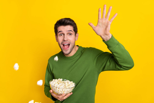 Photo of charming shocked guy dressed green pullover throwing pop corn isolated yellow color background. - Photo, Image