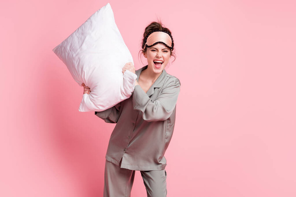 Portrait of cheerful person arms hold cushion open mouth smile look camera isolated on pink color background. - Zdjęcie, obraz