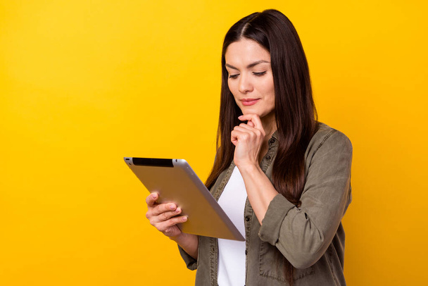 Zdjęcie myślących młoda kobieta myśleć wygląd trzymać za ręce tabletkę izolowane na żółtym tle koloru. - Zdjęcie, obraz