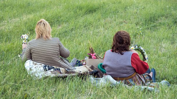 ラトビア、 REKU KALNS - 6月21 、 2022:女性は花の牧草地で花冠を作ります。真夏の休日のお祝い｜Ligo inラトビア - 写真・画像