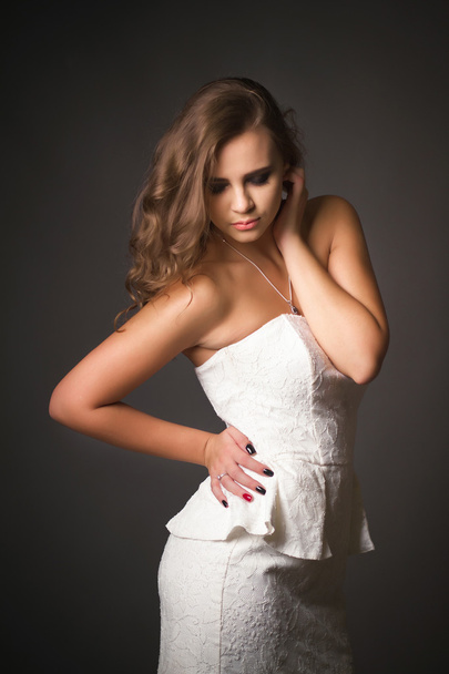 Beautiful woman in white dress against a dark background - Фото, изображение