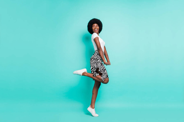 Photo of charming cute dark skin woman dressed casual outfit looking back empty space isolated turquoise color background. - Fotó, kép