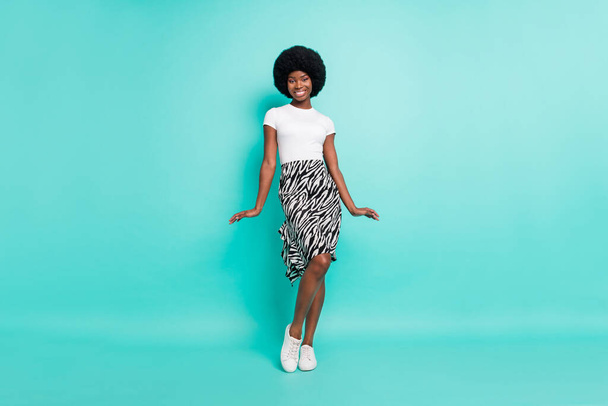 Photo of flirty shy dark skin lady wear casual clothes walking smiling isolated teal color background. - Photo, Image