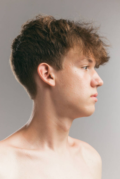 Profile view of young man, teen isolated on grey studio background. Concept of teenage skin care, health, cosmetics for problem skin, youth. Art, fashion, healthy lifestyle and ad - Fotoğraf, Görsel