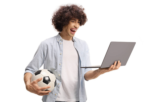 Happy excited guy holding a laptop computer and a football isolated on white background - Photo, Image