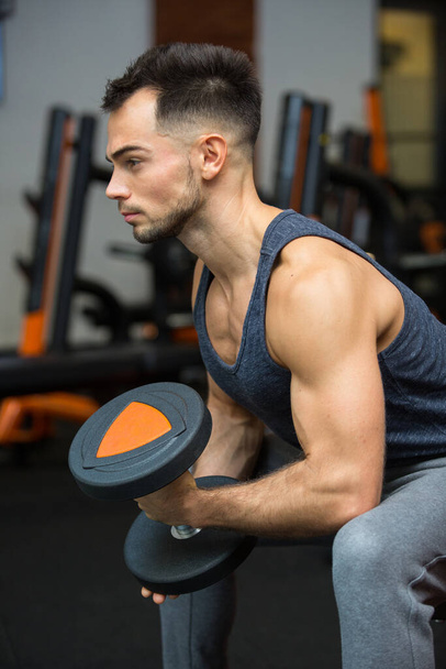 young man working out biceps in front of a mirro - Foto, afbeelding