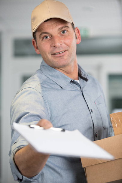 happy delivery man asking for signature - Foto, Bild