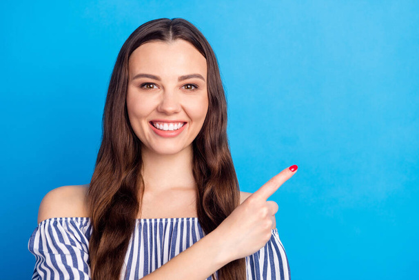 Photo portrait woman pointing finger copyspace smiling recommending advising isolated vivid blue color background. - Фото, изображение