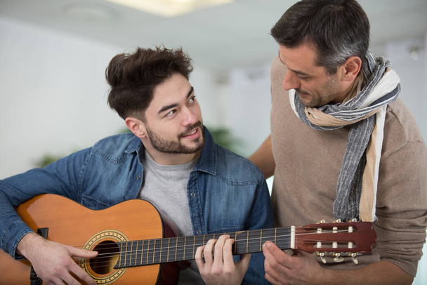 guy with his father resting and playing guitar - Photo, image