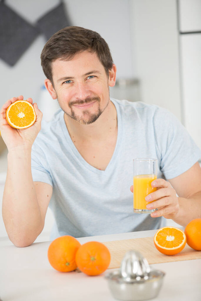 smiling man drinking a glass of fresh orange juice - Foto, afbeelding