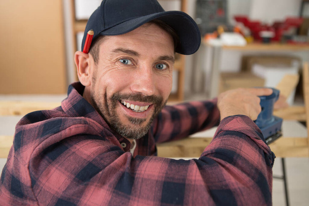 happy male carpenter cutting wood planks - Zdjęcie, obraz