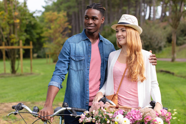 multiracial couple with bicycle standing in the park - Photo, Image