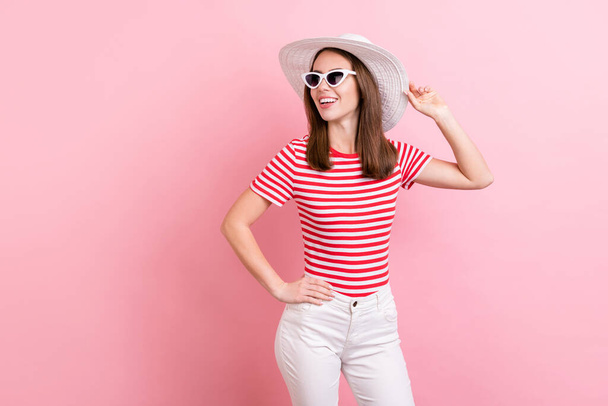 Photo of curious millennial brunette lady look empty space wear cap eyewear striped t-shirt isolated on pink color background. - Foto, Imagen